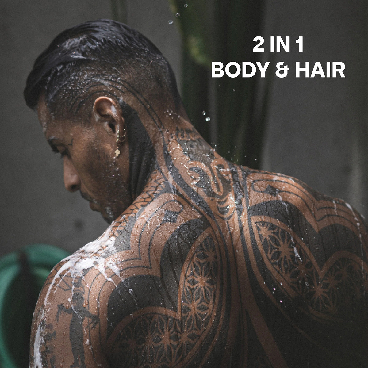 Mand med våde tatoveringer bruger Bali Gents Shower Gel Rosemary Ginger 1 200ml under bruser, 2-i-1 til krop og hår.