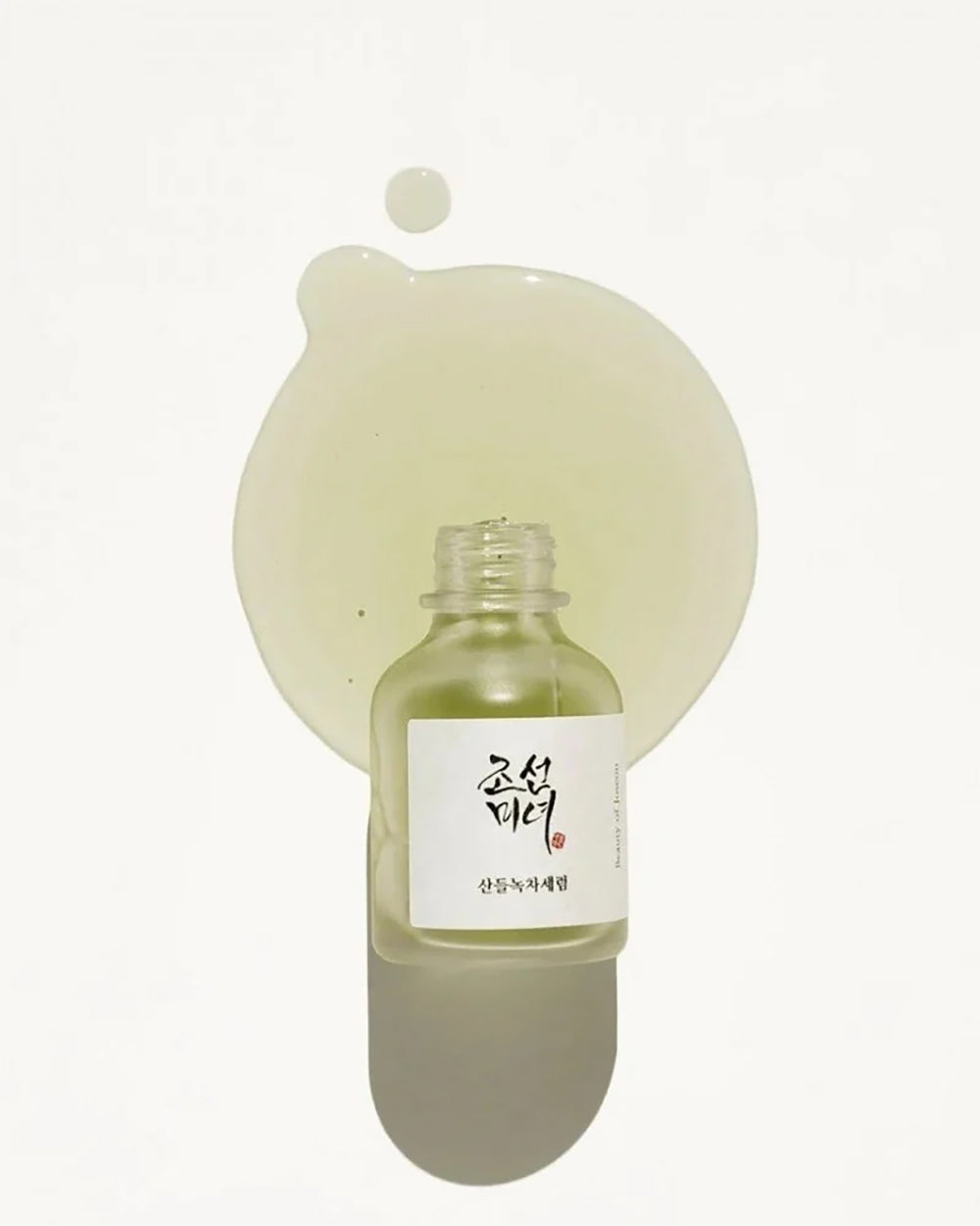Flaske med Beauty of Joseon Calming Serum: Green tea + Panthenol 30ml ovenpå dryp af lysegrønt serum på hvid baggrund.