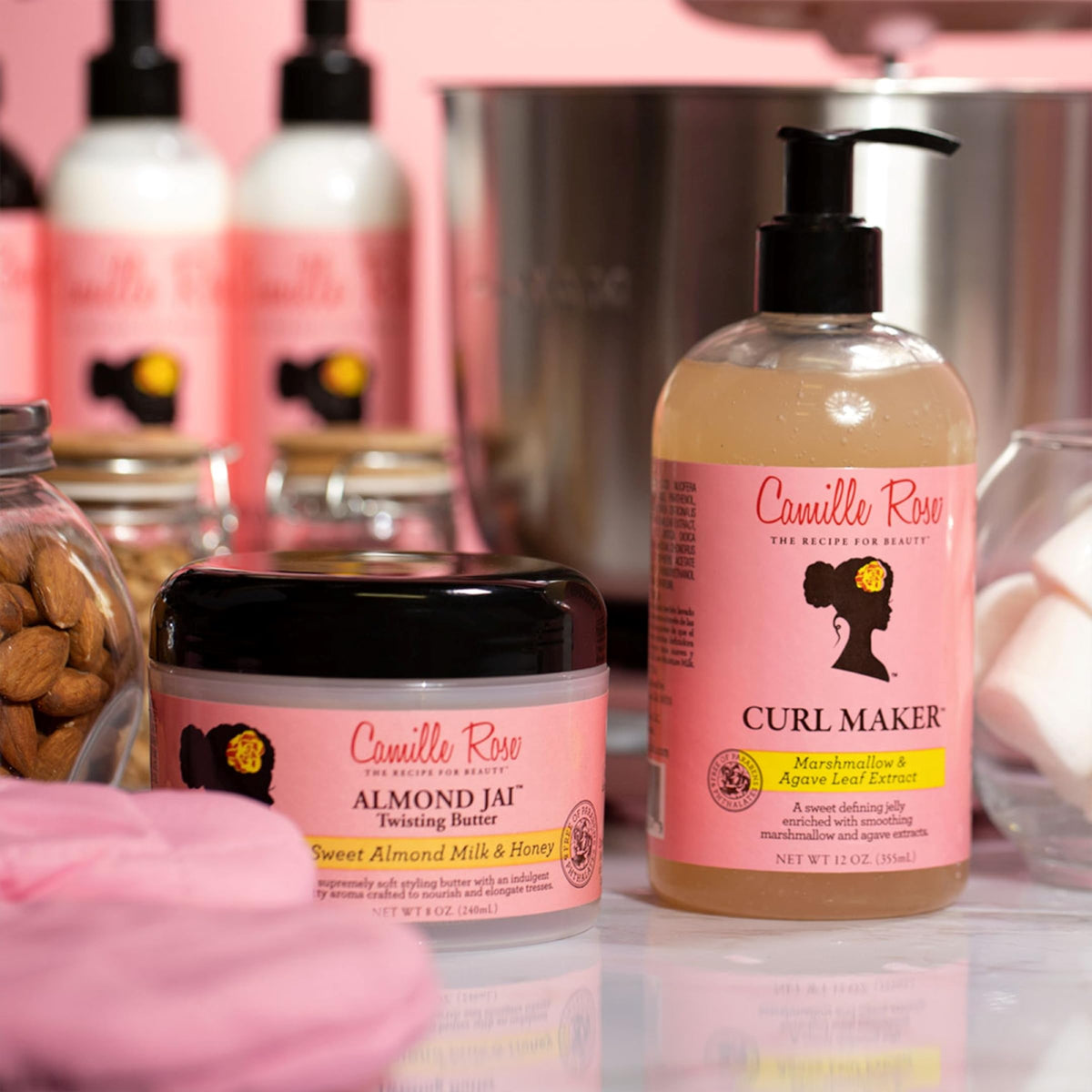 Hvid plastikflaske med en sort pumpe og rosa låg indeholdende Camille Rose Curl Maker hårprodukt.