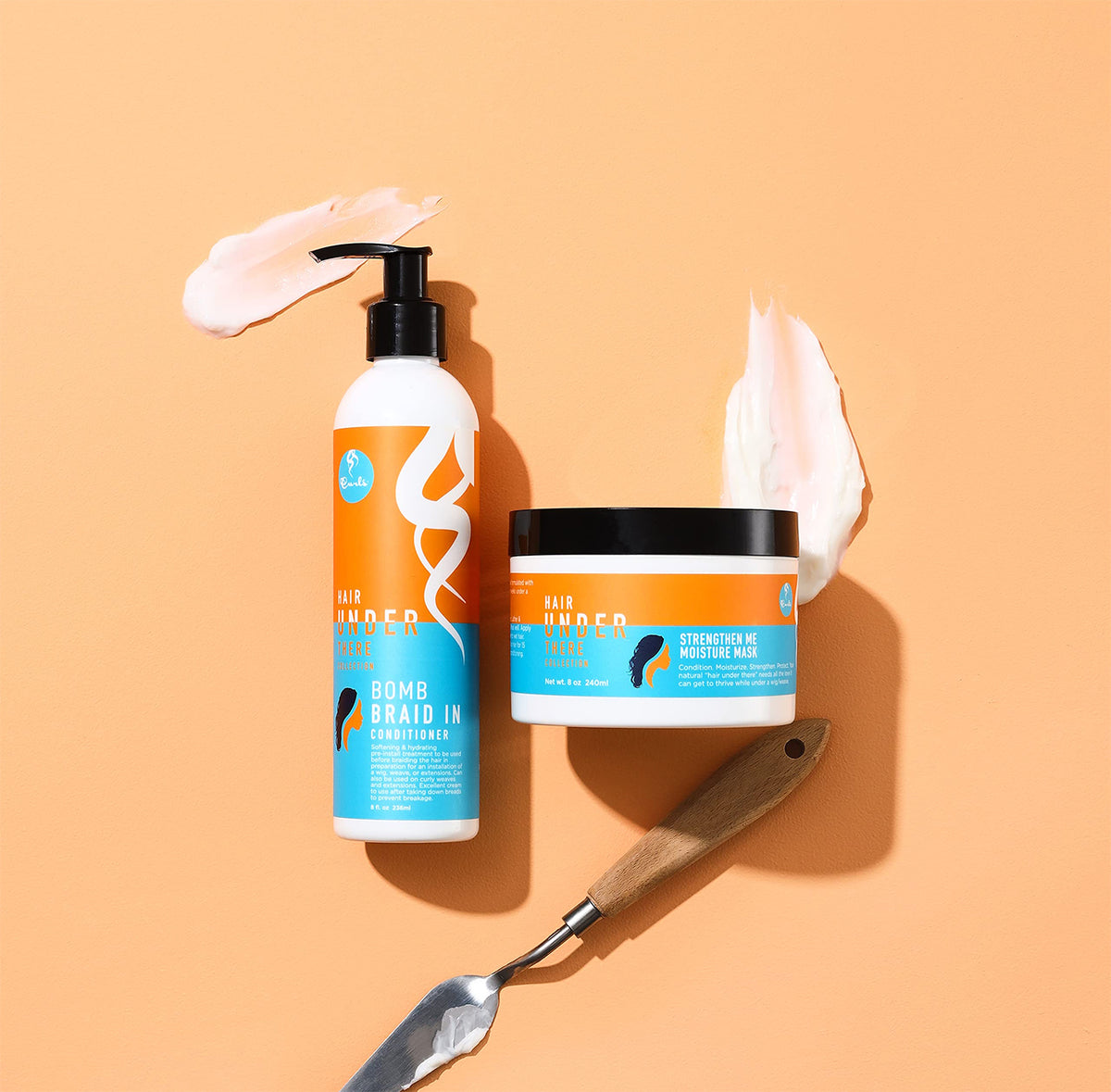 Curls Hair Under There Bomb Braid In Conditioner og Strengthen Me Moisture Mask på orange baggrund med produktprøver og spatel. 