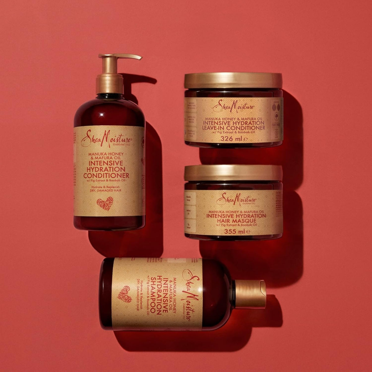 SheaMoisture Manuka Honey & Mafura Oil Intensive Hydration serie med shampoo, balsam, hårmaske og leave-in på rød baggrund.