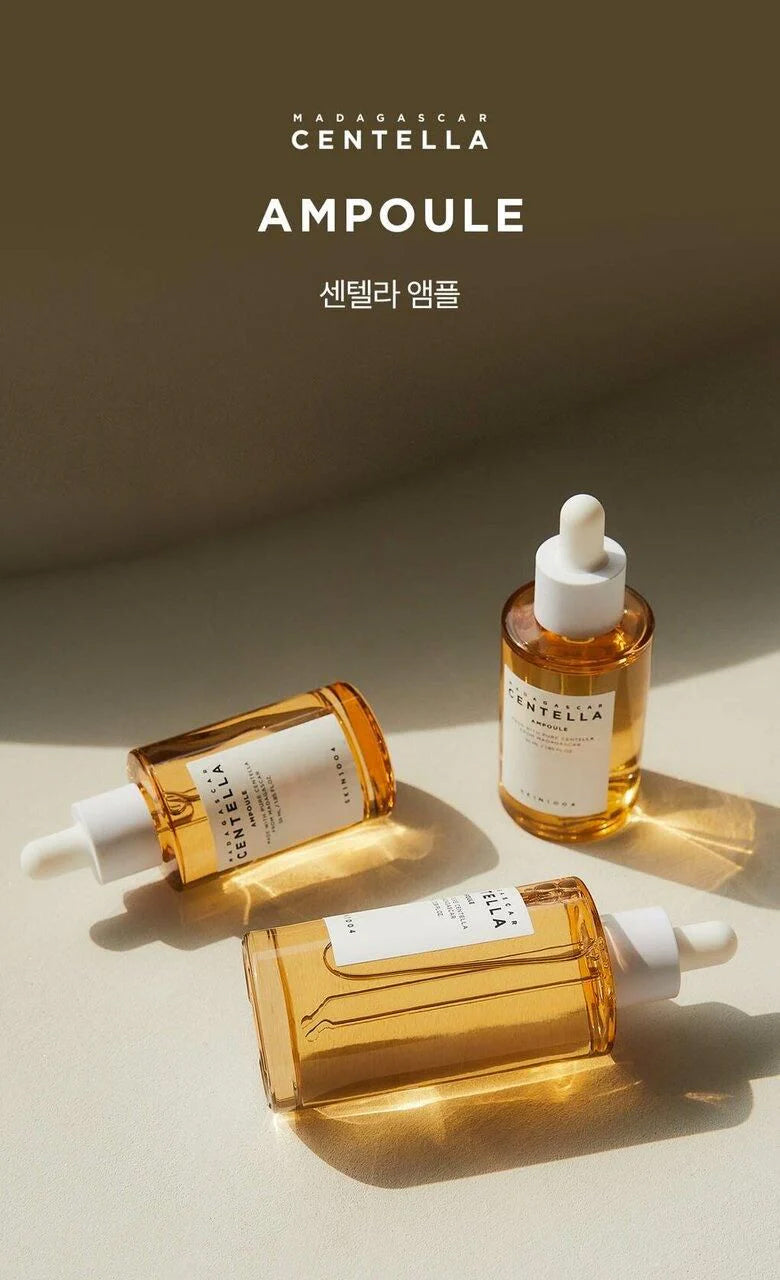 Tre flasker SKIN1004 Madagascar Centella Ampoule 55ml med gylden serum på lys overflade i sollys.